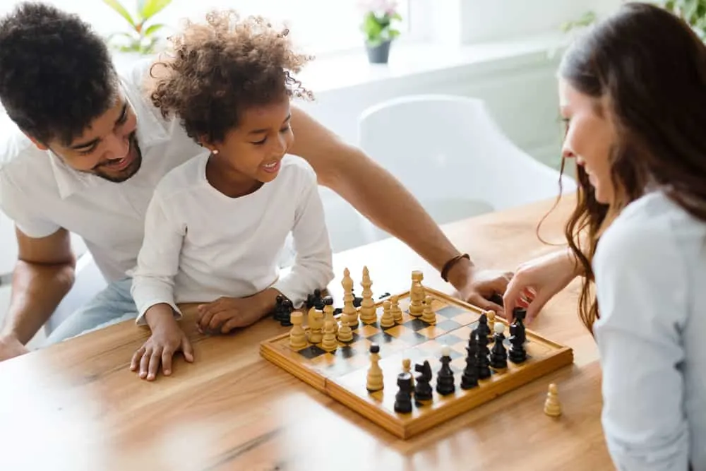 criança jogando xadrez com adultos